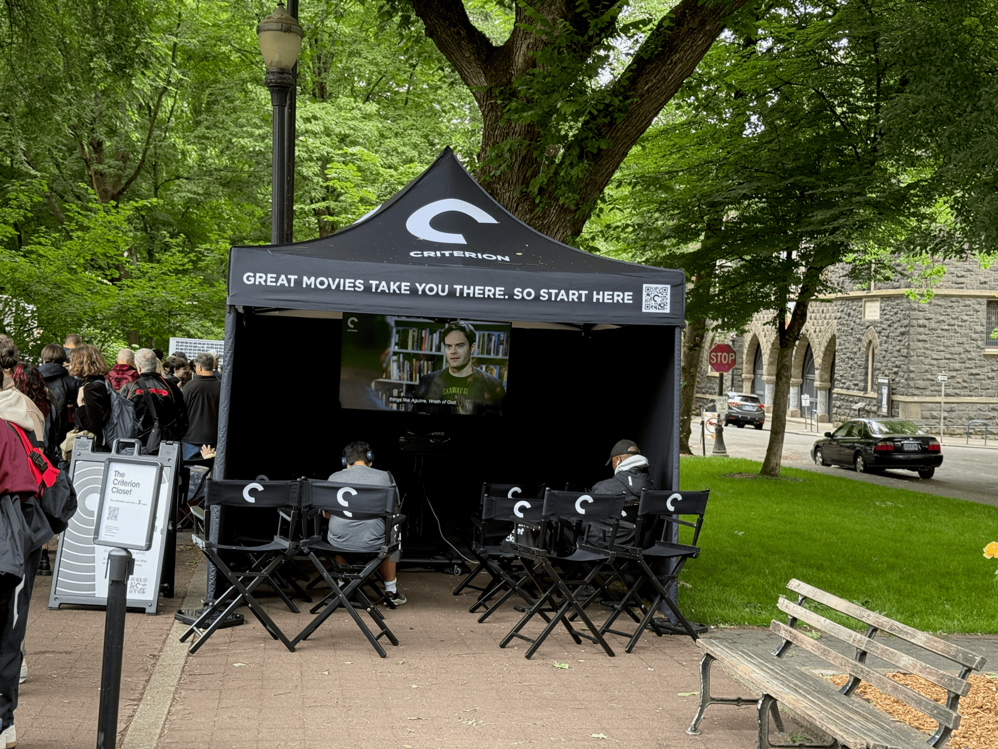 A tent with a bunch of director chairs with the Criterion logo on them, and at the back of the tent there's a video screen with Bill Hader on it.