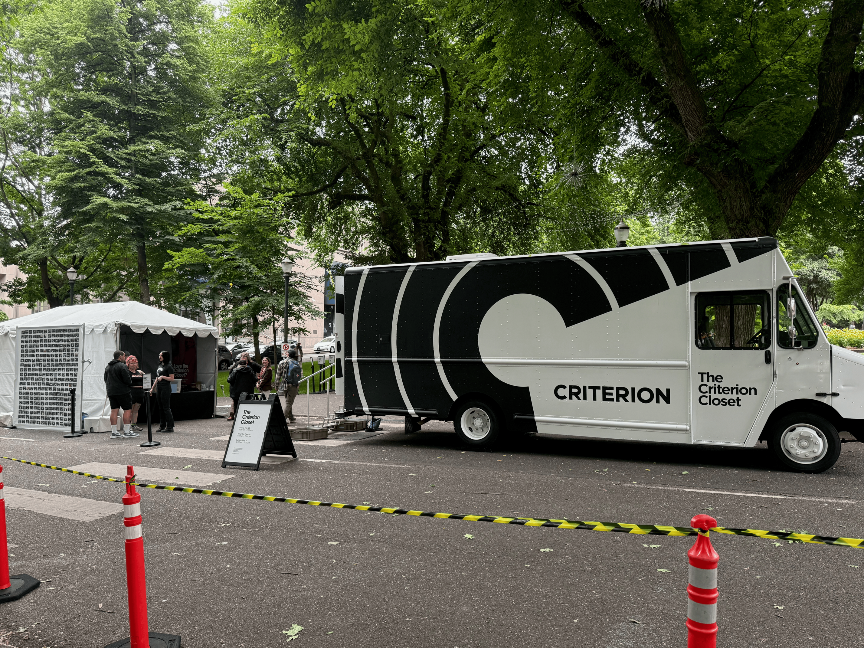 A large step van with the Criterion logo and the words 'The Criterion Closet' on the side. There’s a small tent set up behind it with a few Criterion employees milling around.